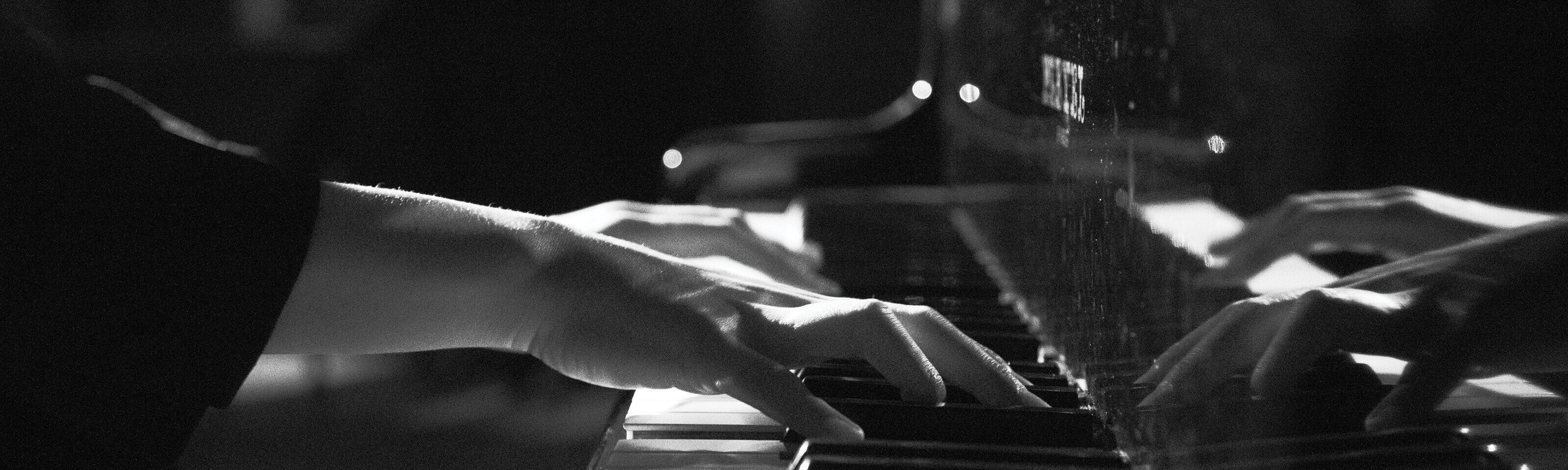 un dettaglio in bianco e nero delle mani di un pianista sulla tastiera