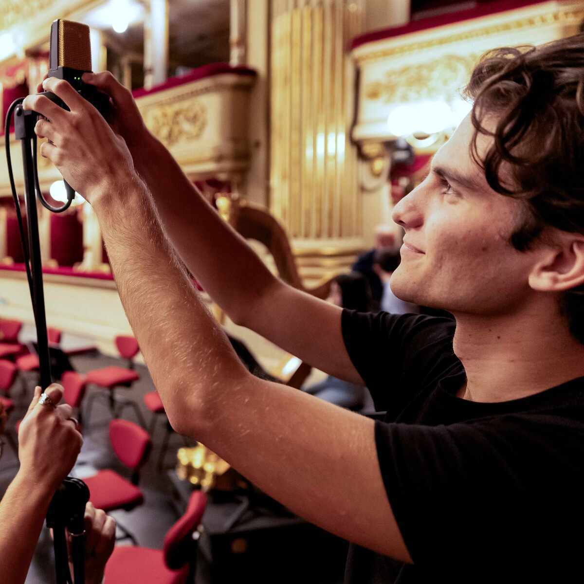 Un giovane tecnico del suono che prepara un microfono per la ripresa di un evento live in teatro